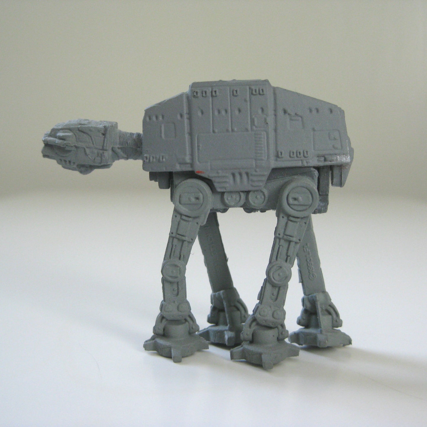 A miniature plastic AT-AT toy standing on all fours, ready to attack.