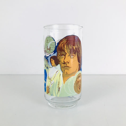 A 1977 Star Wars glass tumbler featuring images of Luke Skywalker, Obi-Wan Kenobi, and Princess Leia.
