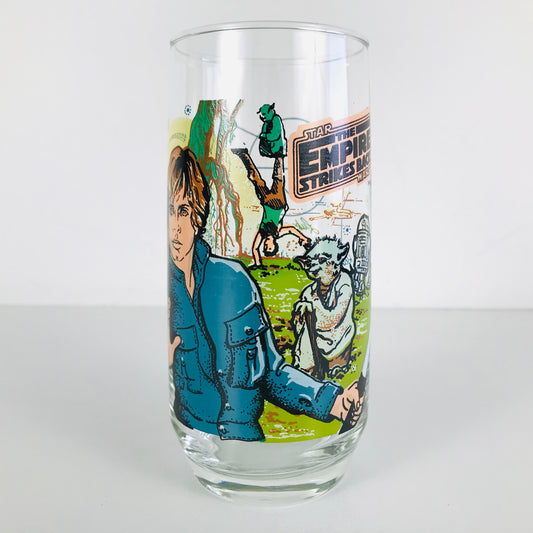Front image of a 1980 Star Wars glass tumbler featuring images of Luke Skywalker, Yoda, and R2-D2 during Luke's Jedi training on the planet Dagobah.