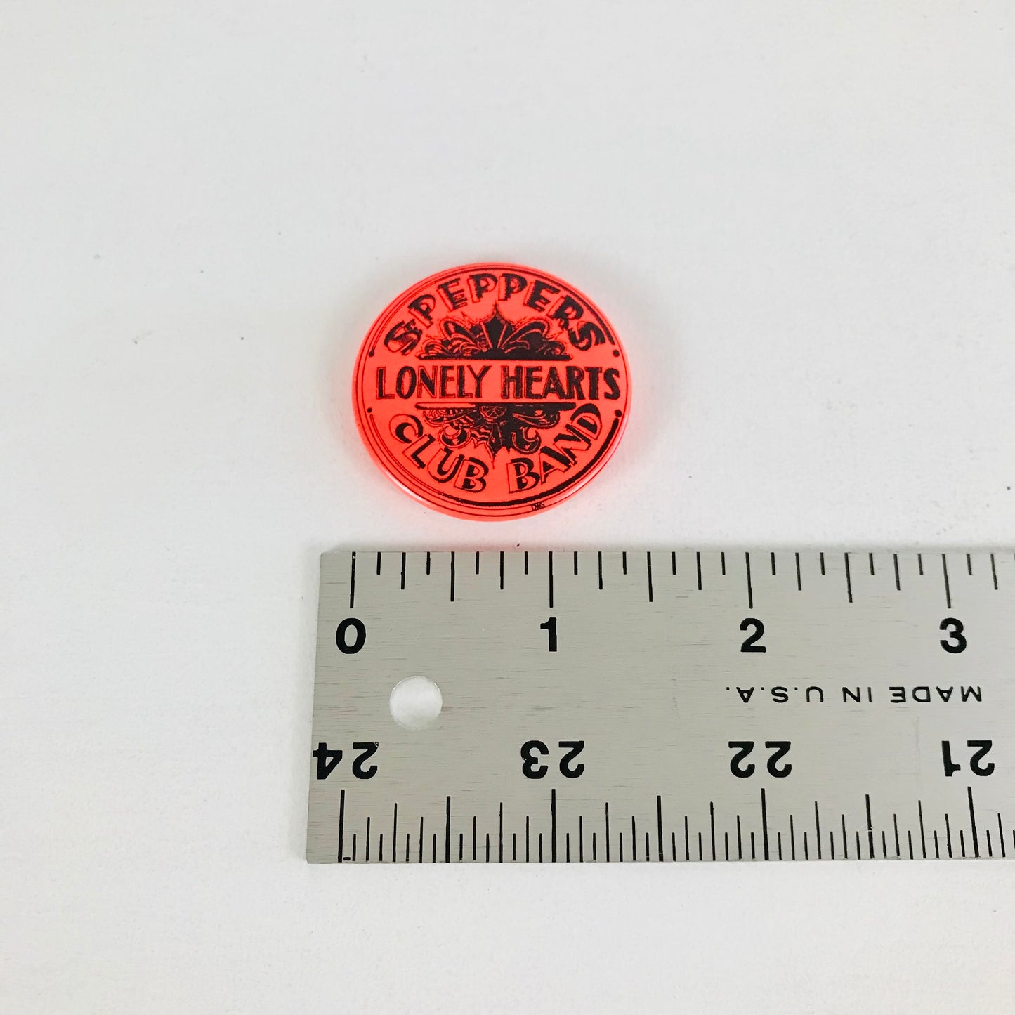 A ruler showing the measurement for a vintage Beatles pinback button.