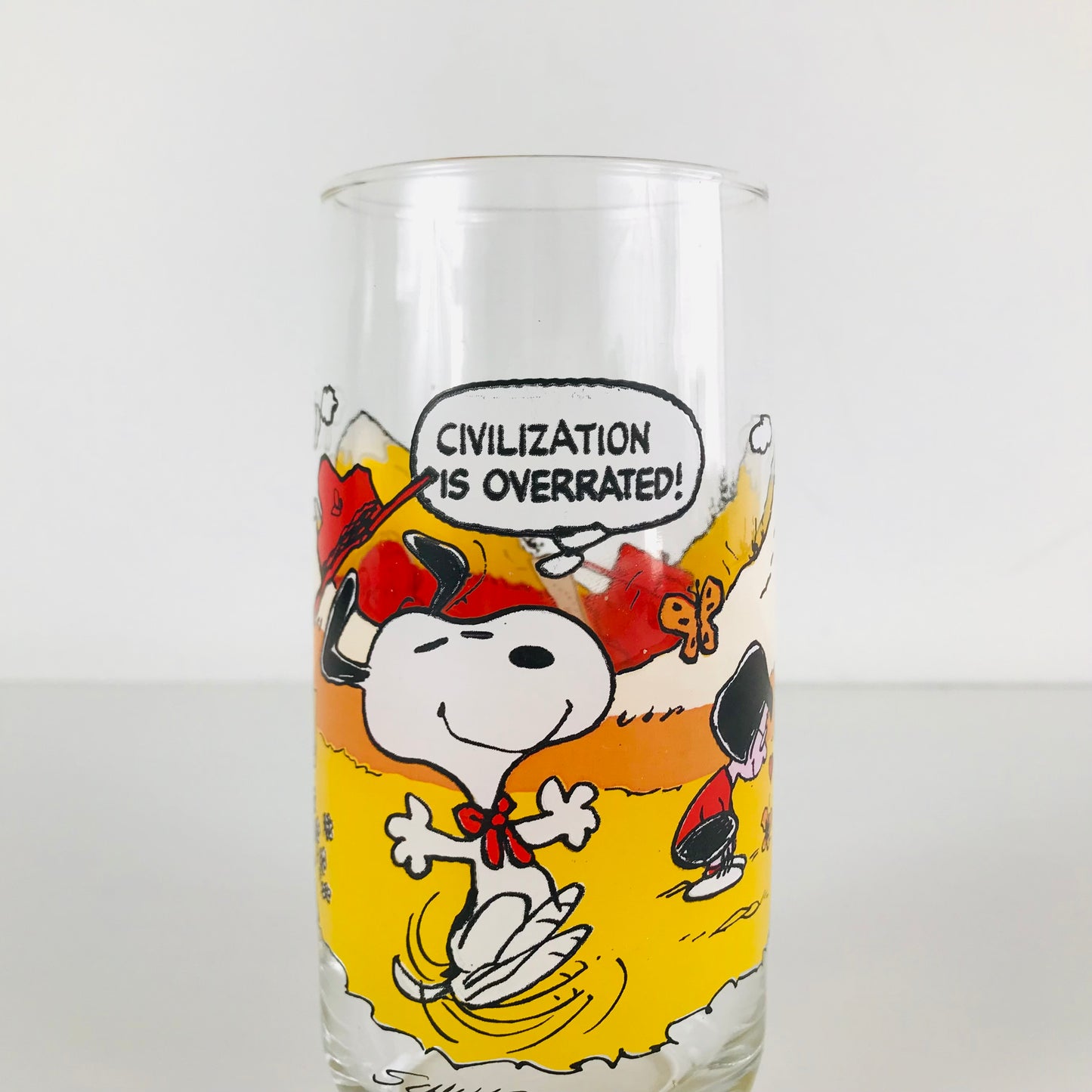 A 1983 Peanuts McDonald's glass tumbler with an image of Snoopy and a speech bubble that reads "Civilization Is Overrated!".