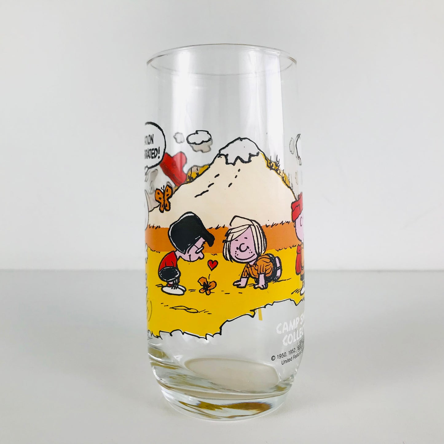 Side of a 1983 McDonald's Peanuts glass tumbler showing Marcie and Peppermint Patty playing with a butterfly.